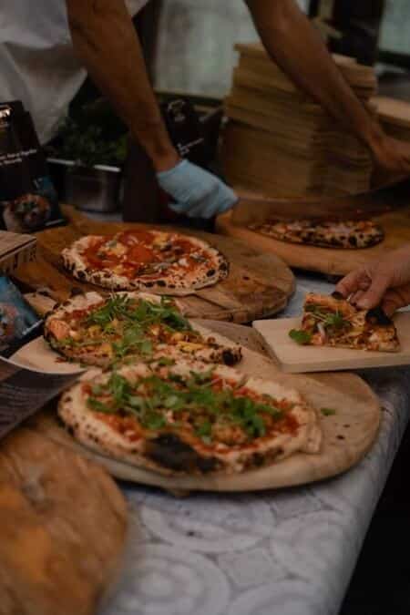 Team dat samen pizza's bakt tijdens teambuilding activiteit, lachend met bloem en deeg.